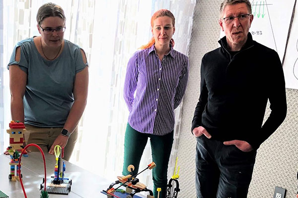 Three LSP Facilitators overlooking LEGO models during an activity.