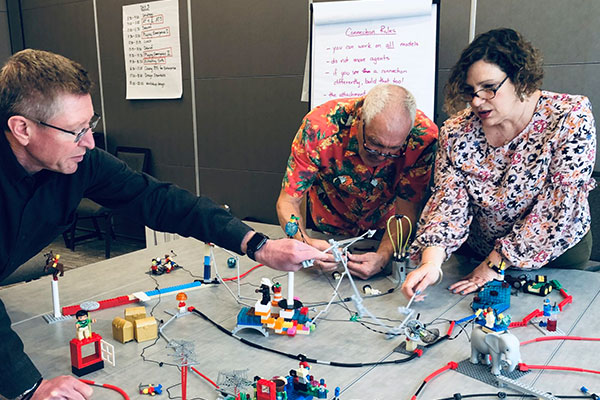 Three participants working on a LEGO landscape activity.